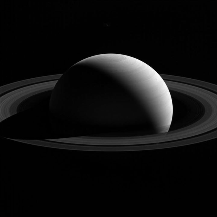 An illusion of perspective, Saturn’s moon Tethys seems to hang above the planet’…