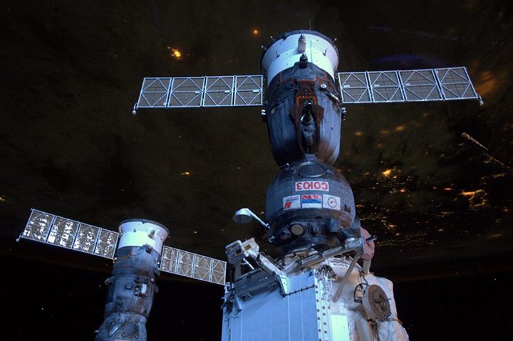“Earth still covered in darkness, but the International Space Station is lit by …
