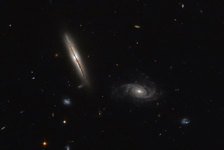 Despite its unassuming appearance, the edge-on spiral galaxy seen here on the le…